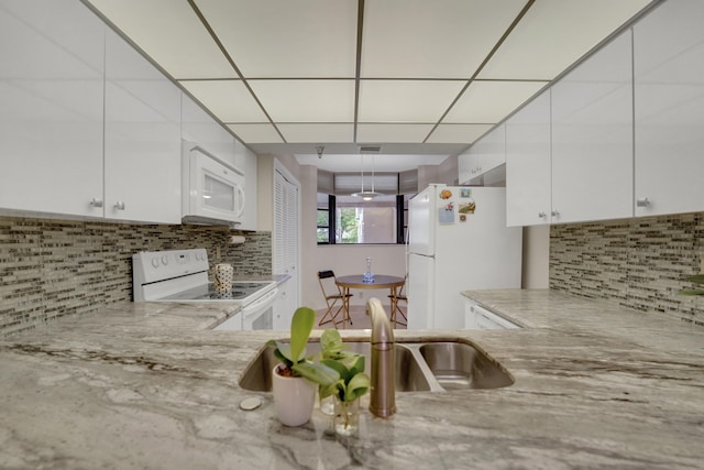 kitchen with backsplash, white appliances, white cabinets, and sink