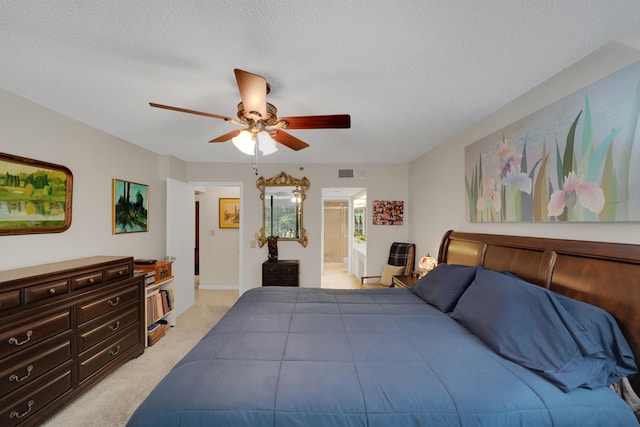 bedroom with ceiling fan, connected bathroom, light colored carpet, and a textured ceiling