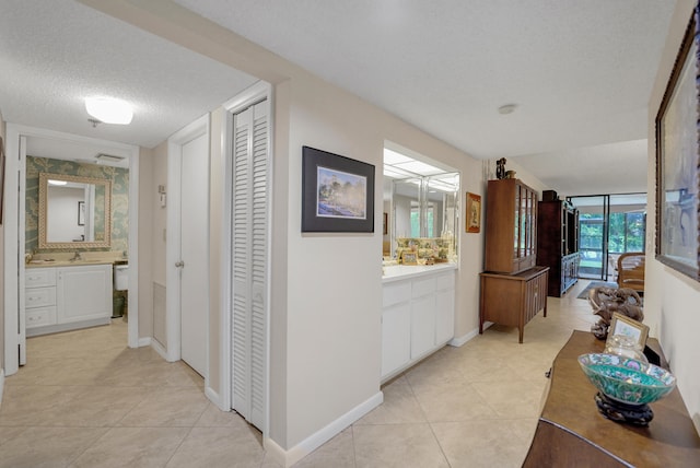 corridor featuring a textured ceiling, light tile patterned floors, and sink