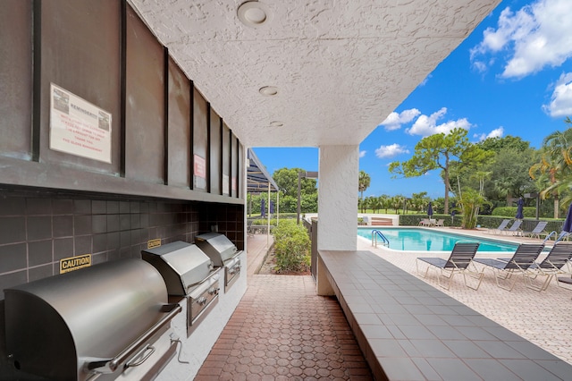 view of patio with a grill, a community pool, and area for grilling