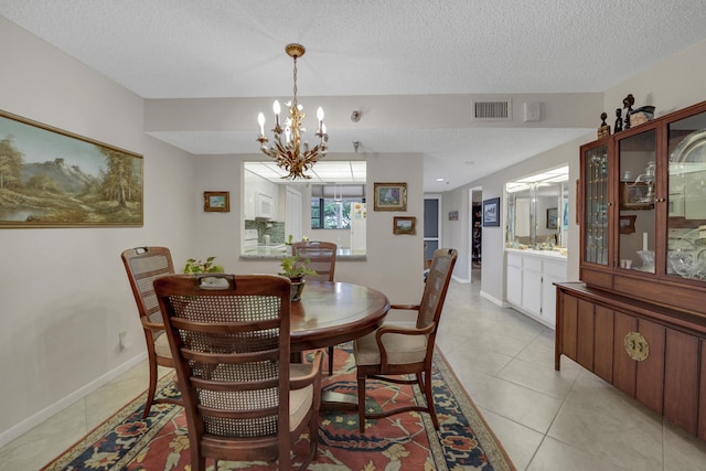 dining space featuring a textured ceiling, an inviting chandelier, and light tile patterned floors