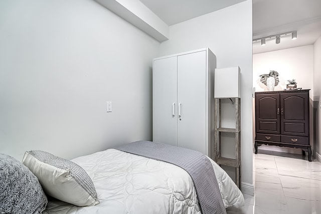 bedroom featuring track lighting, light tile patterned flooring, and a closet