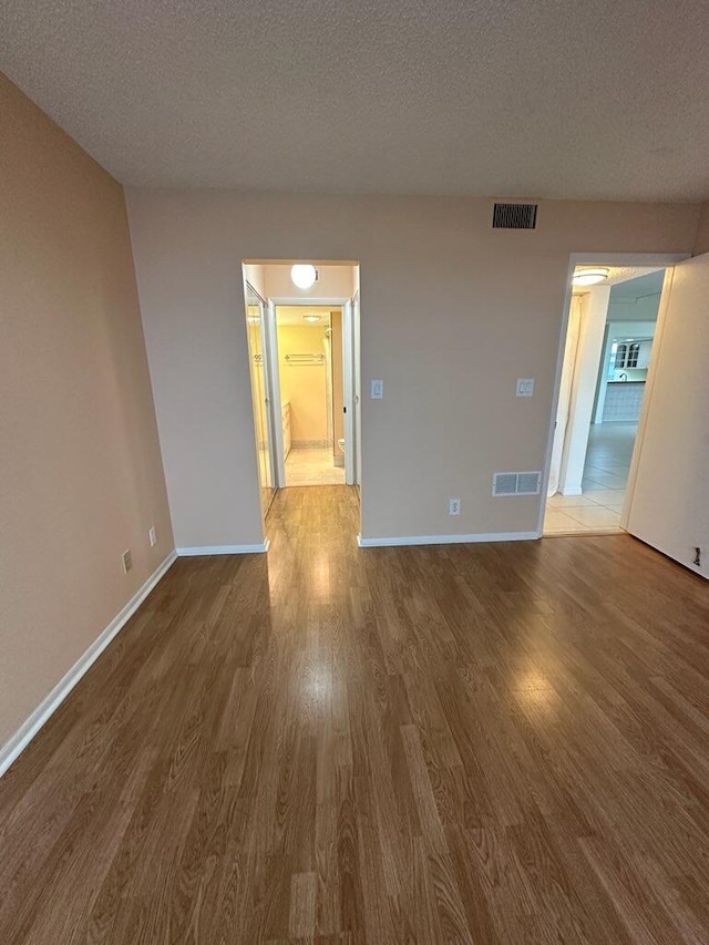 empty room featuring a textured ceiling and hardwood / wood-style floors