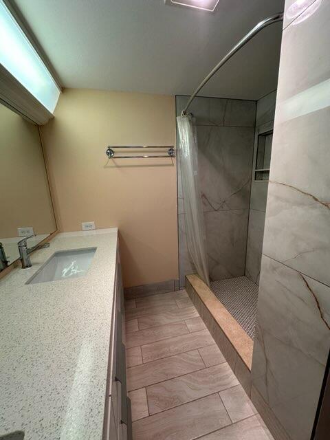 bathroom featuring tile patterned floors, walk in shower, and vanity