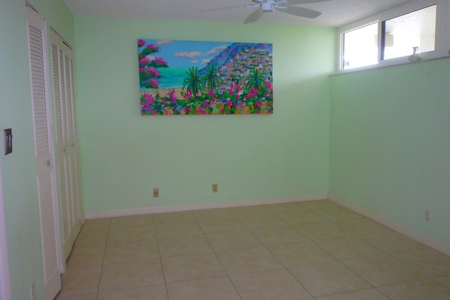 tiled spare room with ceiling fan