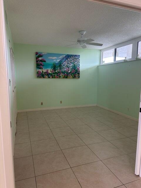 spare room with ceiling fan, a textured ceiling, and tile patterned floors