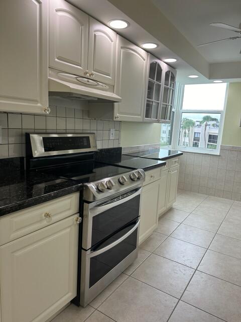 kitchen featuring ceiling fan, decorative backsplash, range with two ovens, and light tile patterned floors