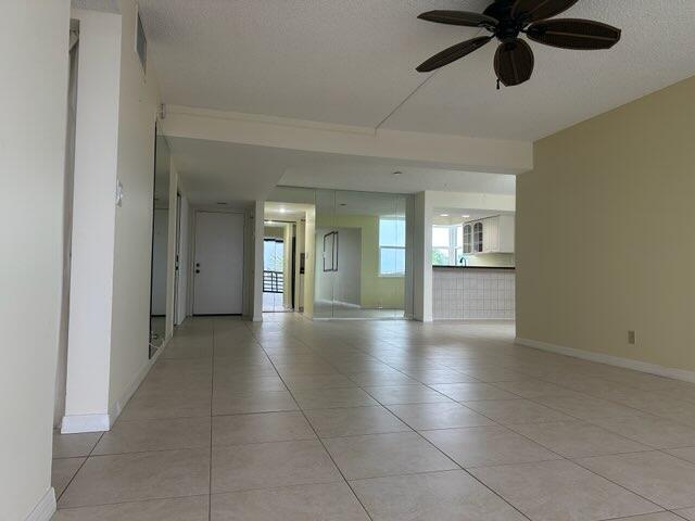 tiled empty room with a textured ceiling and ceiling fan