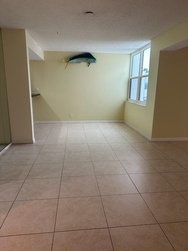 unfurnished room featuring a textured ceiling and light tile patterned floors