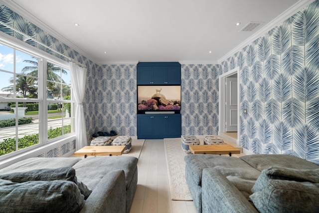 living area featuring visible vents, light wood-style flooring, wallpapered walls, and crown molding
