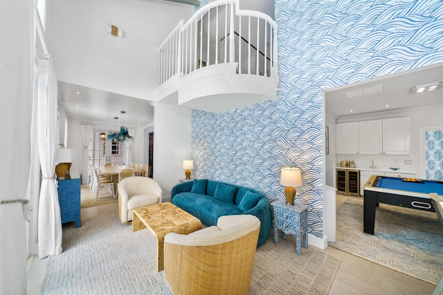 living room featuring recessed lighting, a towering ceiling, an accent wall, crown molding, and light wood-type flooring