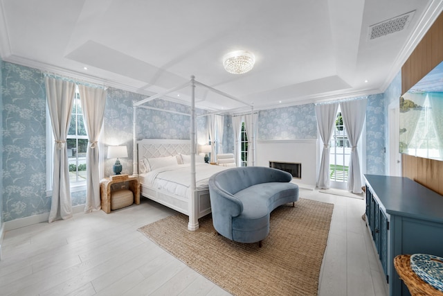 bedroom featuring wallpapered walls, a raised ceiling, visible vents, and ornamental molding