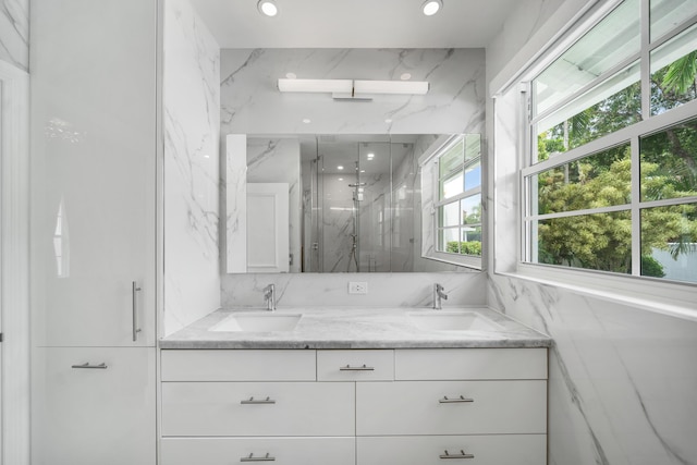 full bathroom with a sink, a marble finish shower, recessed lighting, and double vanity