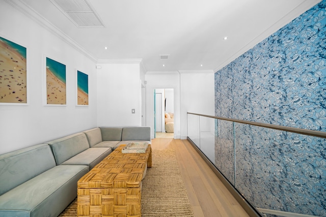 living area featuring light wood-style flooring, visible vents, and ornamental molding