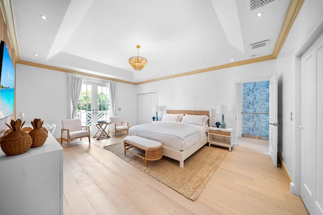 bedroom featuring a tray ceiling, french doors, light wood-type flooring, and visible vents