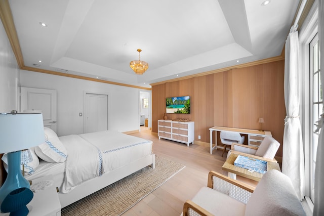 bedroom featuring a tray ceiling, light wood-style flooring, visible vents, and ornamental molding