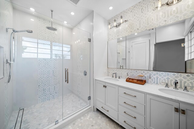 bathroom featuring decorative backsplash, vanity, and a shower with shower door