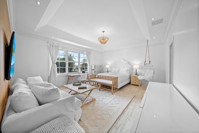 bedroom with visible vents, ornamental molding, a tray ceiling, and wood finished floors