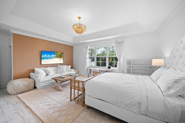 bedroom featuring a tray ceiling, crown molding, wood-type flooring, and an inviting chandelier