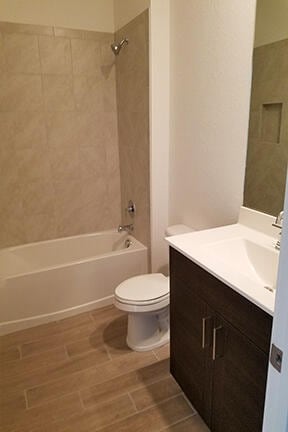 full bathroom with vanity, hardwood / wood-style floors, tiled shower / bath combo, and toilet