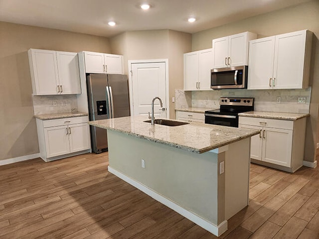 kitchen featuring a center island with sink, light wood-type flooring, sink, and appliances with stainless steel finishes