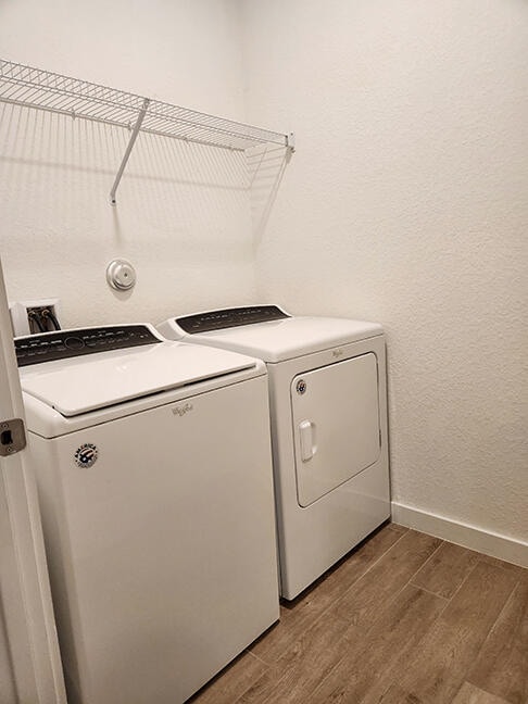 washroom with washing machine and dryer and hardwood / wood-style flooring