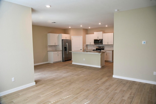 kitchen with a center island with sink, white cabinets, light wood-type flooring, and appliances with stainless steel finishes