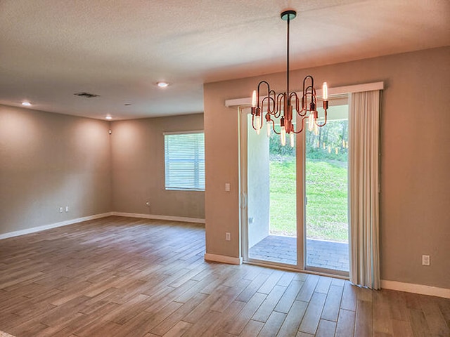 interior space featuring an inviting chandelier, a textured ceiling, and hardwood / wood-style flooring