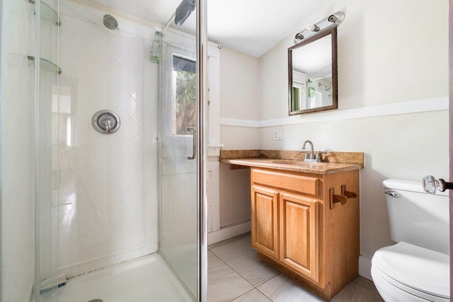 bathroom with a shower with door, toilet, vanity, and tile patterned floors