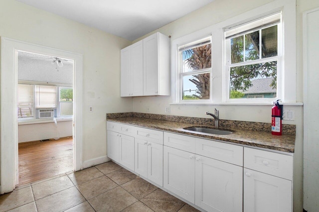 kitchen with cooling unit, white cabinets, sink, light hardwood / wood-style flooring, and dark stone counters