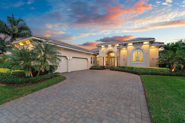 mediterranean / spanish-style home with a garage and a lawn