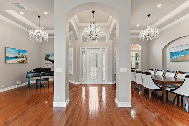 foyer entrance featuring a raised ceiling, a chandelier, and wood-type flooring