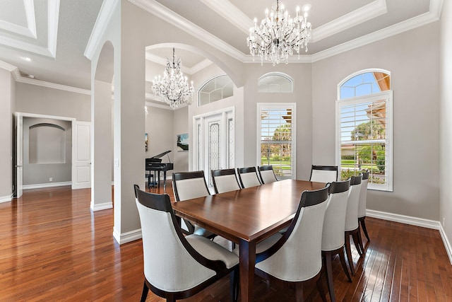 dining area featuring dark hardwood / wood-style flooring, a raised ceiling, an inviting chandelier, and ornamental molding