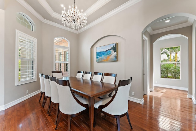 dining room with crown molding, wood-type flooring, a notable chandelier, and a tray ceiling