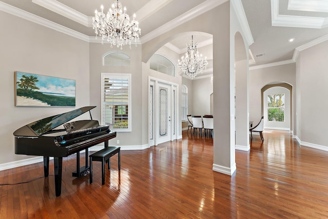 foyer featuring an inviting chandelier, crown molding, a tray ceiling, and wood-type flooring