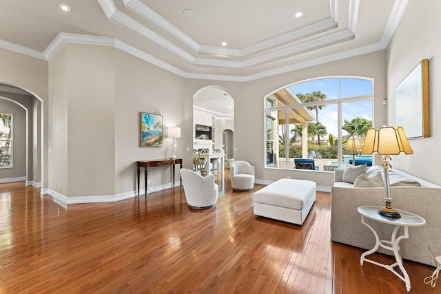 living room featuring crown molding, a tray ceiling, and wood-type flooring