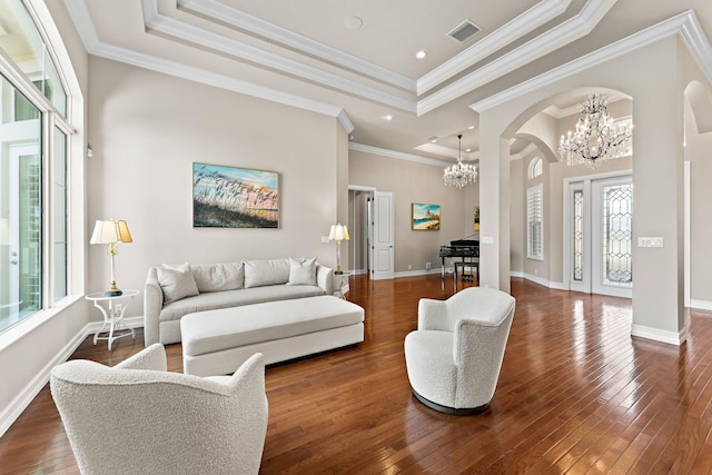 living room with a tray ceiling, hardwood / wood-style floors, ornamental molding, and a chandelier