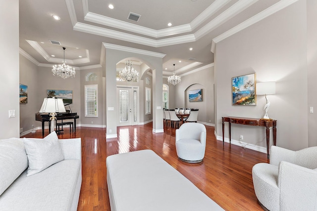 living room featuring plenty of natural light, crown molding, a raised ceiling, and wood-type flooring