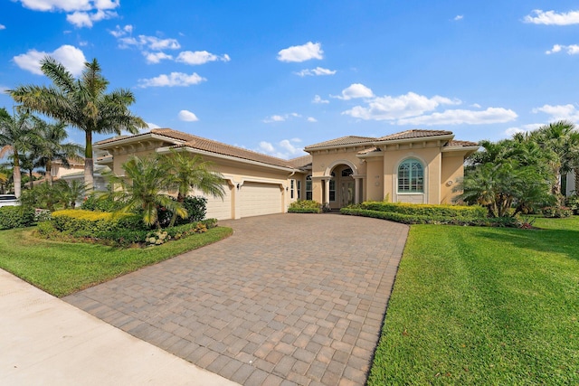 mediterranean / spanish house featuring a tile roof, an attached garage, decorative driveway, a front lawn, and stucco siding