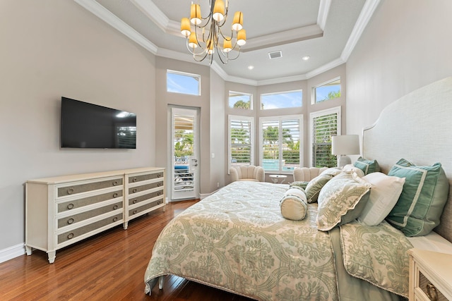 bedroom featuring a tray ceiling, multiple windows, hardwood / wood-style flooring, and a chandelier