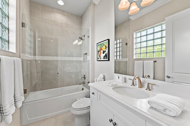 full bathroom with tile patterned floors, vanity, bath / shower combo with glass door, crown molding, and toilet