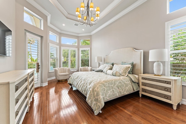 bedroom featuring a chandelier, a tray ceiling, a high ceiling, hardwood / wood-style flooring, and crown molding