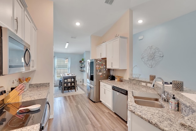 kitchen featuring light stone counters, white cabinets, stainless steel appliances, light hardwood / wood-style flooring, and sink