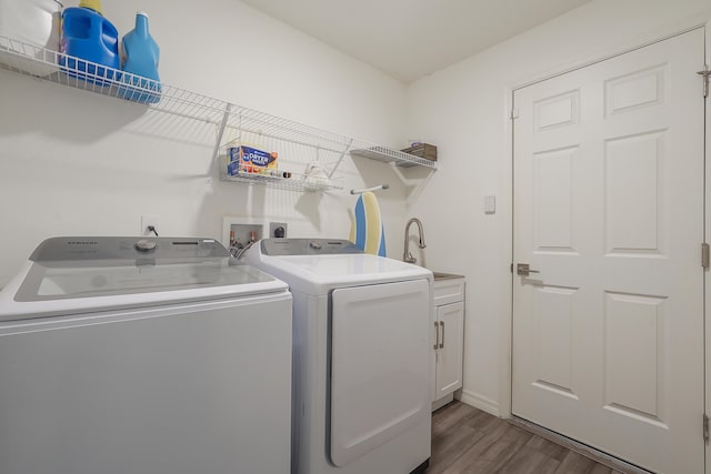 washroom with cabinets, sink, independent washer and dryer, and hardwood / wood-style flooring