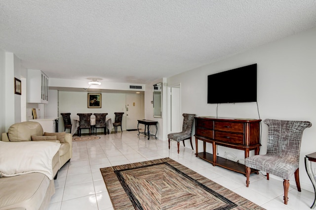 living area featuring visible vents, a textured ceiling, and light tile patterned flooring