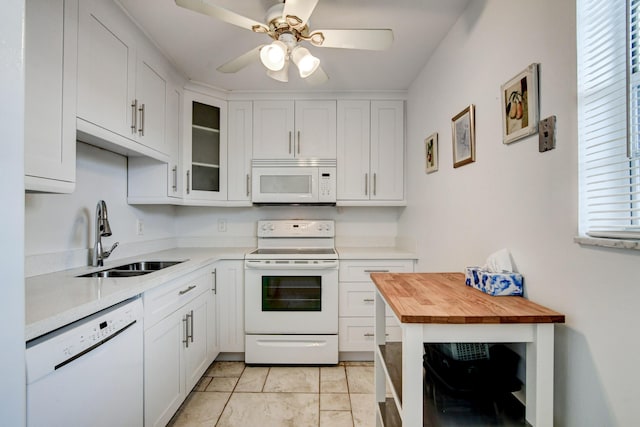 kitchen with white appliances, butcher block countertops, a sink, and white cabinets