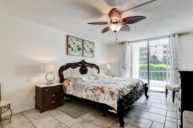 bedroom featuring access to exterior, a textured ceiling, baseboards, and a wall of windows