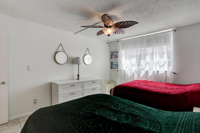 bedroom featuring ceiling fan, baseboards, a textured ceiling, and light tile patterned flooring