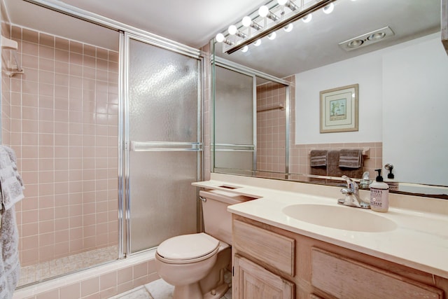 bathroom with vanity, a shower stall, and toilet