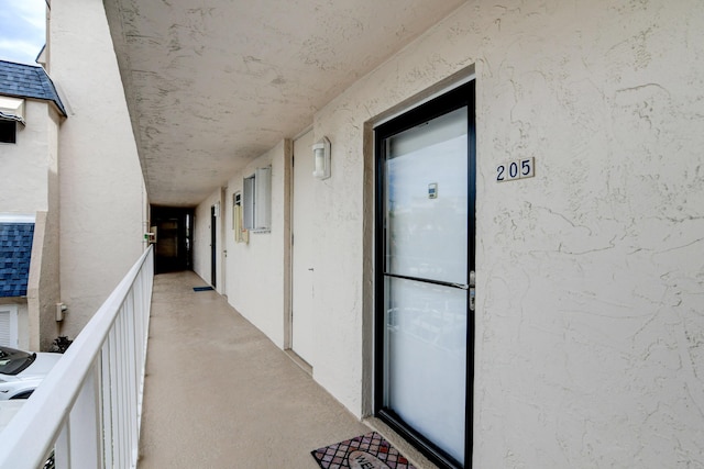 view of exterior entry with a shingled roof and stucco siding